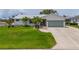 Charming single-story home featuring a lush green lawn, metal roof, and meticulously maintained landscaping with palm trees at 817 Eagle Ln, Apollo Beach, FL 33572