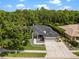 Aerial view of a well-maintained home with lush green landscaping, a long driveway, and a two-car garage at 8401 Ashford Pl, Trinity, FL 34655