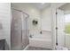 Bright bathroom featuring a glass-enclosed shower, a soaking tub, and stylish tile flooring at 8401 Ashford Pl, Trinity, FL 34655