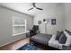 Modern bedroom with sleek black metal bed, hardwood floors, and stylish gaming setup by the window at 8401 Ashford Pl, Trinity, FL 34655