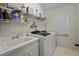 Functional laundry area with a sink, white washer and dryer, and shelving for supplies at 8401 Ashford Pl, Trinity, FL 34655