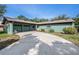 Inviting single-story home featuring a long driveway, lush lawn, and tasteful landscaping with a unique dark green exterior at 8517 Woodwick Ct, Tampa, FL 33615