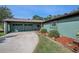 Inviting single-story home featuring a long driveway, lush lawn, and tasteful landscaping with a unique dark green exterior at 8517 Woodwick Ct, Tampa, FL 33615