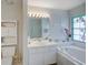 Bright bathroom featuring a soaking tub with stained glass window, a sink, and a full wall mirror at 934 Lucas Ln, Oldsmar, FL 34677