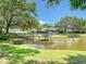 Scenic gazebo perched on a pond with a connecting wooden walkway, surrounded by lush greenery and mature trees at 934 Lucas Ln, Oldsmar, FL 34677