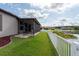 Well-maintained backyard featuring a screened-in lanai, lake view, and white picket fence at 12352 Crestridge Loop, New Port Richey, FL 34655