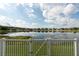 Scenic view of a tranquil lake reflecting blue skies and clouds, seen from a fenced backyard at 12352 Crestridge Loop, New Port Richey, FL 34655