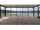View of a serene lake from a brick-paved screened lanai featuring a white picket fence at 12352 Crestridge Loop, New Port Richey, FL 34655