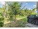 A view of the home's spacious backyard with lush greenery and a grill at 1594 Cassius St, Lutz, FL 33549