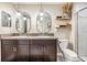 Bathroom featuring double vanity, granite countertop, stylish mirrors, and a walk-in shower at 1594 Cassius St, Lutz, FL 33549