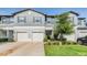 Charming townhome featuring a gray exterior, white garage doors, and well-maintained landscaping at 1594 Cassius St, Lutz, FL 33549