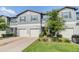 Charming townhome featuring a gray exterior, white garage doors, and well-maintained landscaping at 1594 Cassius St, Lutz, FL 33549