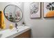 Chic powder room featuring a modern sink, round mirror, and decorative art at 1594 Cassius St, Lutz, FL 33549