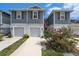 Charming two-story townhome showcasing a gray exterior, inviting garages, and vibrant flowering landscaping at 2140 Laceflower Dr, Brandon, FL 33510