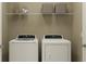 Bright laundry room features front load washer and dryer set with shelving for storage at 2274 Blue Grosbeak Pl, Wimauma, FL 33598
