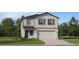 Charming two-story home featuring a two-car garage, well-manicured lawn, and inviting blue front door at 2278 Blue Grosbeak Pl, Wimauma, FL 33598