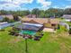 Aerial view of a home with a screened-in pool, lush lawn, and landscaped yard with mature trees at 2436 Covington Ave, Spring Hill, FL 34608