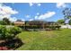 Serene backyard with a screened pool area bordered by lush greenery and a manicured lawn at 2436 Covington Ave, Spring Hill, FL 34608