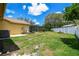 Large backyard with green lawn, screened-in pool, white fence and mature trees at 2436 Covington Ave, Spring Hill, FL 34608