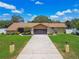 Inviting one-story home showcasing a long driveway, two-car garage, stone accents, and a lush, green lawn at 2436 Covington Ave, Spring Hill, FL 34608