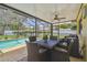 Cozy screened-in patio with a dining set, ceiling fan, and view of the pool and landscaped backyard at 2436 Covington Ave, Spring Hill, FL 34608