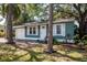 Quaint single-story home featuring blue siding, white trim, and mature trees in a landscaped yard at 2616 47Th N Ave, St Petersburg, FL 33714