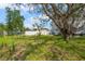 Large backyard with mature trees, grassy lawn, patio, and partial fence at 2700 10Th W St, Palmetto, FL 34221