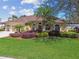 Inviting yellow home featuring lush green lawn, colorful landscaping, and a spacious driveway with a three-car garage at 2712 Clubhouse Dr, Plant City, FL 33566