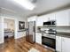 Modern kitchen with stainless steel appliances, white cabinets, and hardwood floors, open to the bedroom at 3213 E Genesee St, Tampa, FL 33610