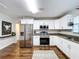 Modern kitchen featuring white cabinets, stainless steel appliances, and granite countertops, with hardwood flooring at 3213 E Genesee St, Tampa, FL 33610