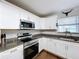 A well-lit kitchen with stainless steel appliances, granite countertops, and white cabinets, featuring hardwood floors at 3213 E Genesee St, Tampa, FL 33610