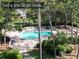 Aerial view of the neighborhood pool, and is surrounded by trees, a fence, and lounge chairs at 36750 Us 19 N Hwy # 3104, Palm Harbor, FL 34684