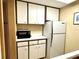 Galley kitchen features white appliances, upper and lower cabinets, and a microwave oven at 36750 Us 19 N Hwy # 3104, Palm Harbor, FL 34684