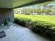 Outdoor patio area with greenery, a brick wall, and a seating area with two green chairs and a table at 36750 Us 19 N Hwy # 3104, Palm Harbor, FL 34684