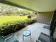 An open patio with brick wall, two chairs, a table, and view of landscaping and parking area at 36750 Us 19 N Hwy # 3104, Palm Harbor, FL 34684
