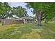 Single-story home surrounded by mature trees and a lush green lawn, enclosed by a wooden fence, offering privacy and charm at 3915 W Leila Ave, Tampa, FL 33616