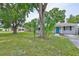 Serene view of a single-story home surrounded by mature trees and a well-maintained lawn, highlighted by a blue front door at 3915 W Leila Ave, Tampa, FL 33616