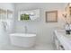 Bright bathroom features a soaking tub, and a vanity with decorative sconces and white paneled accent wall at 509 Buckingham E Ave, Oldsmar, FL 34677