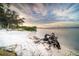Picturesque sandy beach with clear water, mature trees, and a tranquil sky at sunset at 509 Buckingham E Ave, Oldsmar, FL 34677