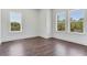 Bright bedroom features dark hardwood floors and two large windows offering natural light and green views at 509 Buckingham E Ave, Oldsmar, FL 34677