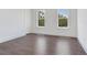 Bright bedroom features dark hardwood floors and two large windows offering natural light and green views at 509 Buckingham E Ave, Oldsmar, FL 34677