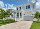 Stunning two-story home featuring white siding, a covered porch, and a two-car garage with brick paved driveway at 509 Buckingham E Ave, Oldsmar, FL 34677