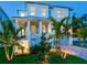Charming two-story home with a well-manicured lawn, lush tropical landscaping, and inviting front porch at twilight at 509 Buckingham E Ave, Oldsmar, FL 34677