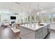 Bright open-concept kitchen with island, modern lighting, dining area, living room, and hardwood floors at 509 Buckingham E Ave, Oldsmar, FL 34677