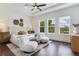 Bright main bedroom features a ceiling fan, plush chairs, and three windows overlooking the verdant landscape at 509 Buckingham E Ave, Oldsmar, FL 34677