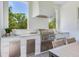 Modern outdoor kitchen featuring a stainless steel grill, ample counter space, and views of lush greenery at 509 Buckingham E Ave, Oldsmar, FL 34677