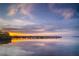 Sunset reflecting off the water highlights a pier stretching into the distance at sunset at 509 Buckingham E Ave, Oldsmar, FL 34677