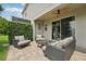 Backyard covered patio with comfortable wicker seating, a ceiling fan, and lush privacy hedge at 513 Harbor Springs Dr, Palm Harbor, FL 34683