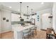 Bright kitchen features white cabinets, tile backsplash, stainless steel appliances, island with seating, and modern pendant lights at 513 Harbor Springs Dr, Palm Harbor, FL 34683