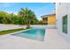 Modern backyard oasis featuring a sparkling pool, white tiled patio, and lush tropical landscaping at 5964 Bayview S Cir, St Petersburg, FL 33707